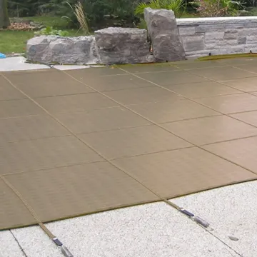 Inground swimming pool safely secured with the taut Doheny's tan mesh safety cover for child and pet protection.