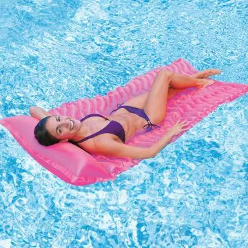 Woman relaxing on a pink inflatable pool lounge float in a swimming pool. She is smiling and wearing a purple bikini, demonstrating the float's comfort and buoyancy.