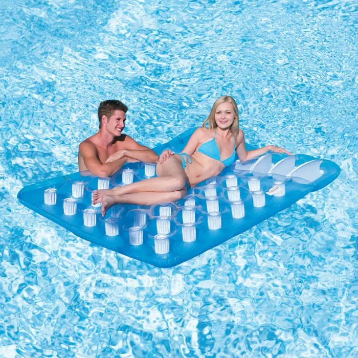A man and a woman are smiling and relaxing on a translucent blue inflatable double pool mattress with 36 circular pockets, floating in a swimming pool.